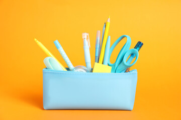 Wall Mural - Different stationery in pencil case on orange background