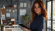 © Abdul Karim - cheerful woman with chestnut brown hair, wearing a navy blue blouse, standing beside her desk with a tablet in hand.