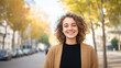 © Helga - A young woman with curly hair, smiling and enjoying the city atmosphere, captured in a vibrant urban environment. curly hair, young woman, city portrait, urban environment, city ba