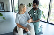 © zinkevych - African American male doctor hand doing physical therapy by extending elbow of mature female patient