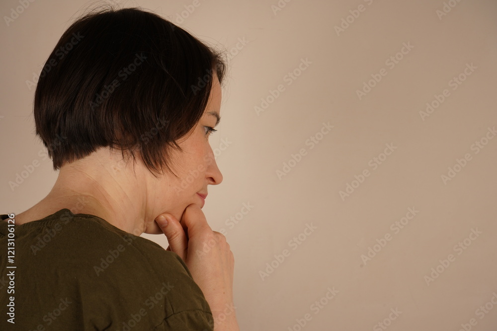 A brunette standing with the back of her head is photographed. She is slightly turned and looks to the side. Her face is photographed in close-up.