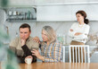 © JackF - Family members quarreling in the kitchen and old woman trying to calm angry man sitting at the table