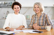 © JackF - Smiling old and middle-aged women posing at the kitchen-table with sheets of paper and laptop in front of them