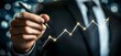 © Ekkarat_Studio - Business Growth Concept with Hand Holding Pen Creating Upward Trend Line on Blurry Background