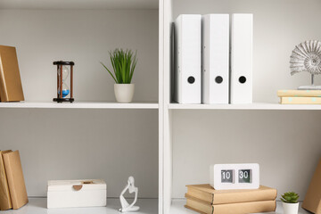 Shelves with books, folders and stylish decor, closeup