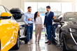 © Prostock-studio - Handsome arab guy sales assistant giding young family husband and wife by newest car salon, cheerful salesman showing appropriate black auto for happy middle-eastern couple, full length shot