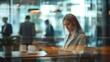 © Abdul - Businesswoman working on tablet in a modern cafe, surrounded by colleagues blurred in the background. A serene atmosphere is captured with warm lighting, highlighting her focused expression.