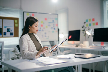 Poster - Businesswoman reviewing financial reports, analyzing sales data, and examining economic growth graph charts in modern office