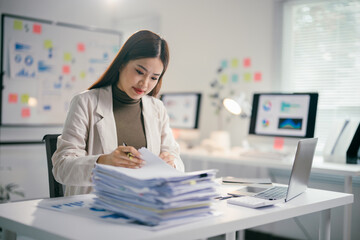 Poster - Professional female analyzing documents while typing on laptop in contemporary workspace