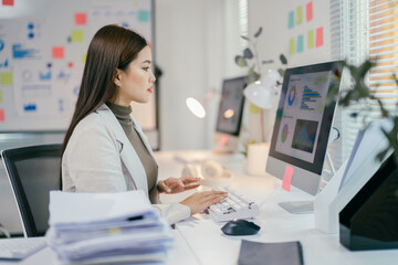 Aufkleber - Asian businesswoman analyzing charts and graphs on computer, improving efficiency and productivity in modern workplace