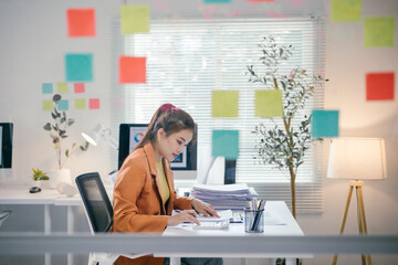 Wall Mural - Young professional working with financial documents and calculator in a bright modern office with colorful sticky notes