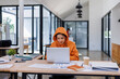 © David - Young asian woman wearing orange shirt hold use laptop pc computer drink coffee sit alone at table in coffee shop cafe restaurant indoors work or study. Freelance mobile office business concept