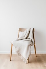 Poster - A simple wooden chair sits on a pale wooden floor, adorned with a soft light gray wool throw. Natural light softly fills the room, creating a calming atmosphere perfect for relaxation