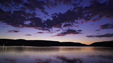 Poster - Stunning sunset over tranquil lake with mountain silhouettes in the background