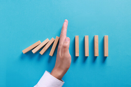 Wall Mural -  - man stopping wooden blocks from falling on light blue background, top view. domino effect