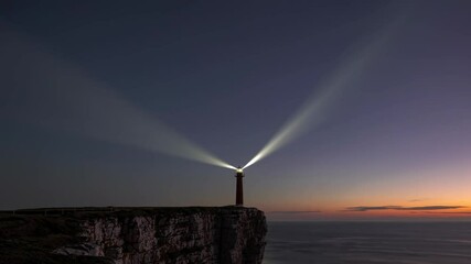 Aufkleber - Lighthouse beams shine over the ocean at dusk in a tranquil coastal setting