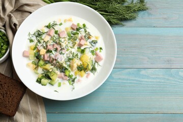 Wall Mural - Delicious okroshka soup in bowl on light blue wooden table, flat lay. Space for text