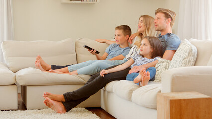 Wall Mural - Family Sitting On Sofa At Home Watching TV Together