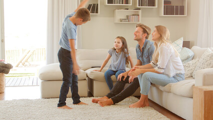 Wall Mural - Family Sitting On Sofa At Home Playing Game Of Charades