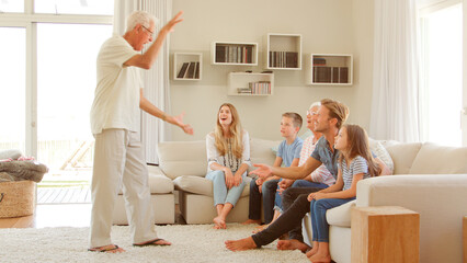 Wall Mural - Multi Generation Family Sitting On Sofa At Home Playing Game Of Charades