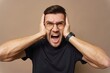 © muse studio - Man expressing extreme frustration with hands on his head in a neutral background setting
