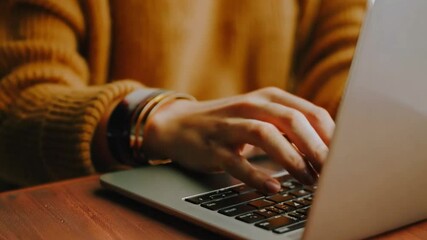 Aufkleber - This Someone is typing on a laptop with focused attention in a warm, inviting space.