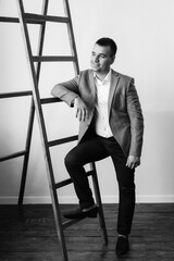 Wall Mural - portrait of a young groom in a blue jacket and white shirt in a bright studio