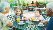 © Monkey Business - Grandparents With Grandchildren At Table Enjoying Snack At Outdoor Cafe Or Restaurant