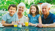 © Monkey Business - Portrait Of Grandparents With Grandchildren At Table Enjoying Snack At Outdoor Cafe Or Restaurant