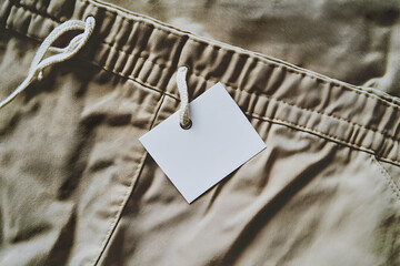 Wall Mural - Blank Clothing Tag on Beige Pants: Mockup for Branding and Design