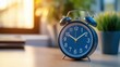 © Khaisan - Close-up shot of a classic blue alarm clock on a wooden surface with a blurry background