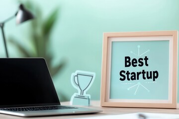 Wall Mural - best startup award displayed on a desk with a laptop.