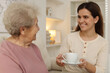 © New Africa - Granddaughter giving hot drink to her grandmother at home. Elderly care