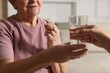 © New Africa - Caregiver giving glass of water to senior woman with medical pill indoors, closeup