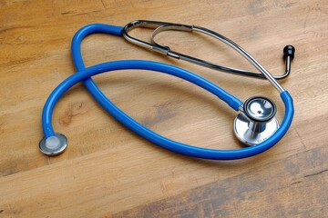 Poster - blue stethoscope on a wooden surface . a stethoscope resting on a wooden floor, showcasing its sleek
