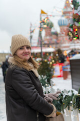 Wall Mural - Woman enjoying winter decorations at a festive market in snowy Moscow during holiday season