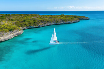 Wall Mural - A sailboat gliding across turquoise waters under a clear blue sky