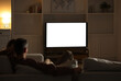 © New Africa - Couple watching TV on sofa at home in evening, back view