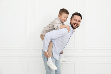 Wall Mural - Happy father and his cute little son near white wall indoors