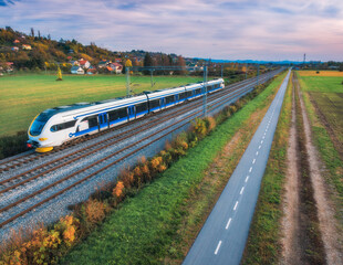 Wall Mural - aerial view of modern high speed train moving near alpine mountains and green fields, bike path at s