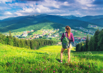 Wall Mural - girl on the hill with yellow flowers and green grass in beautiful alpine mountain valley at sunset i