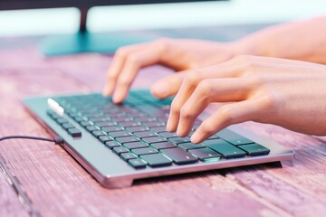 Poster - Close-up of hands typing on a sleek, modern keyboard on a wooden desk.