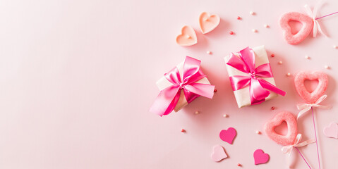Wall Mural - Pink hearts and gift box with ribbon on a light pink background