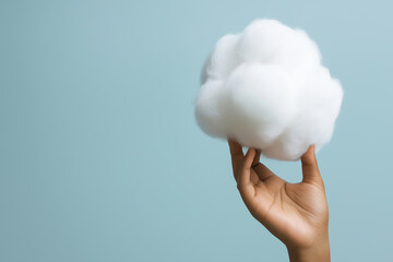 Poster - Soft cotton cloud held in a hand against a light blue background