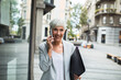 © Davor - Senior professional businesswoman using smartphone downtown