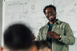 © Zamrznuti tonovi - Smiling black male teacher explaining lesson to students in classroom