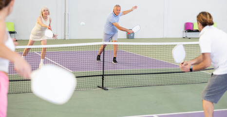 Wall Mural - Man and woman training to play pickleball tennis on the pickleball court indoor