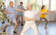 © JackF - Cheerful elderly woman attending group choreography class, learning modern dynamic dances. Concept of active lifestyle of older generation..