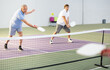 © JackF - Focused resolved elderly man playing friendly pickleball match in team with male partner on indoors court. Concept of concentration in competition