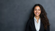 © Alexander - A confident young businesswoman with long hair, smiling at the camera in front of a gray studio backdrop, embodying success and sophistication. confident businesswoman, long hair,